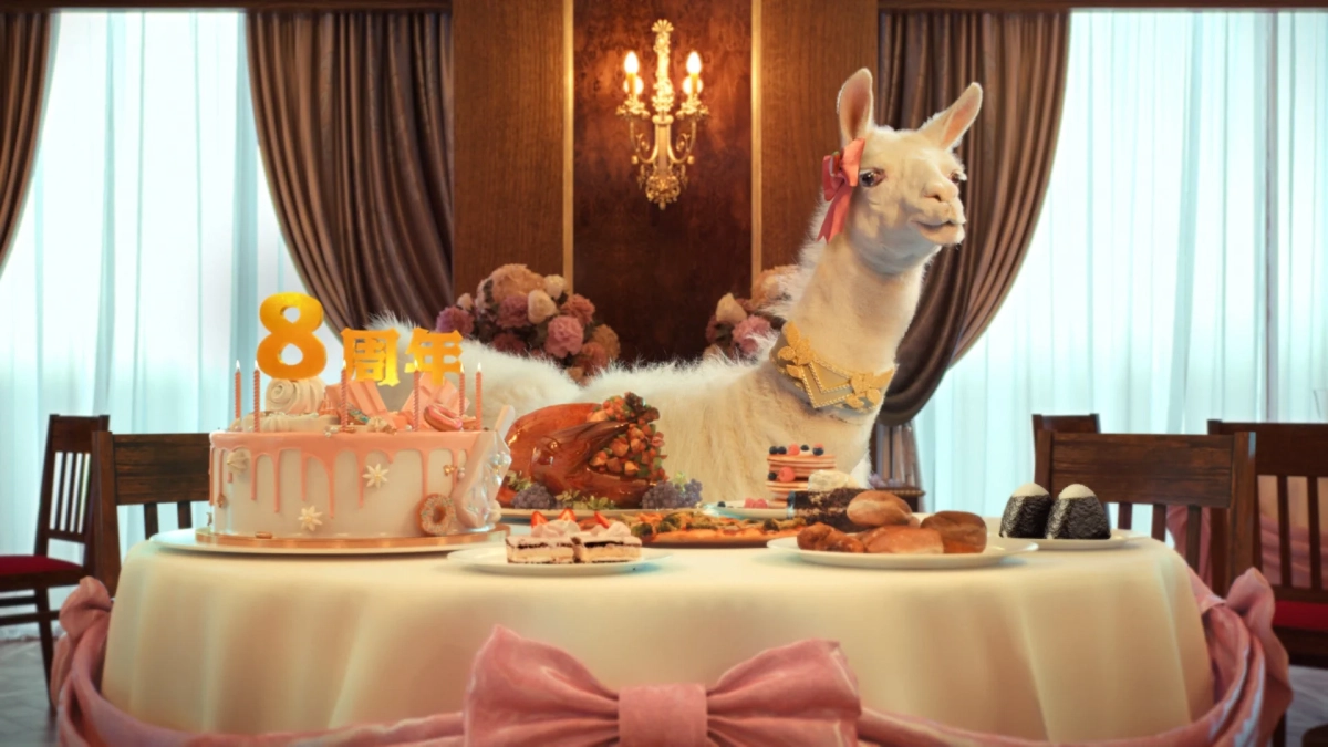 ピンクのリボンと金色の首飾りをつけた白いラマとバースデーケーキ