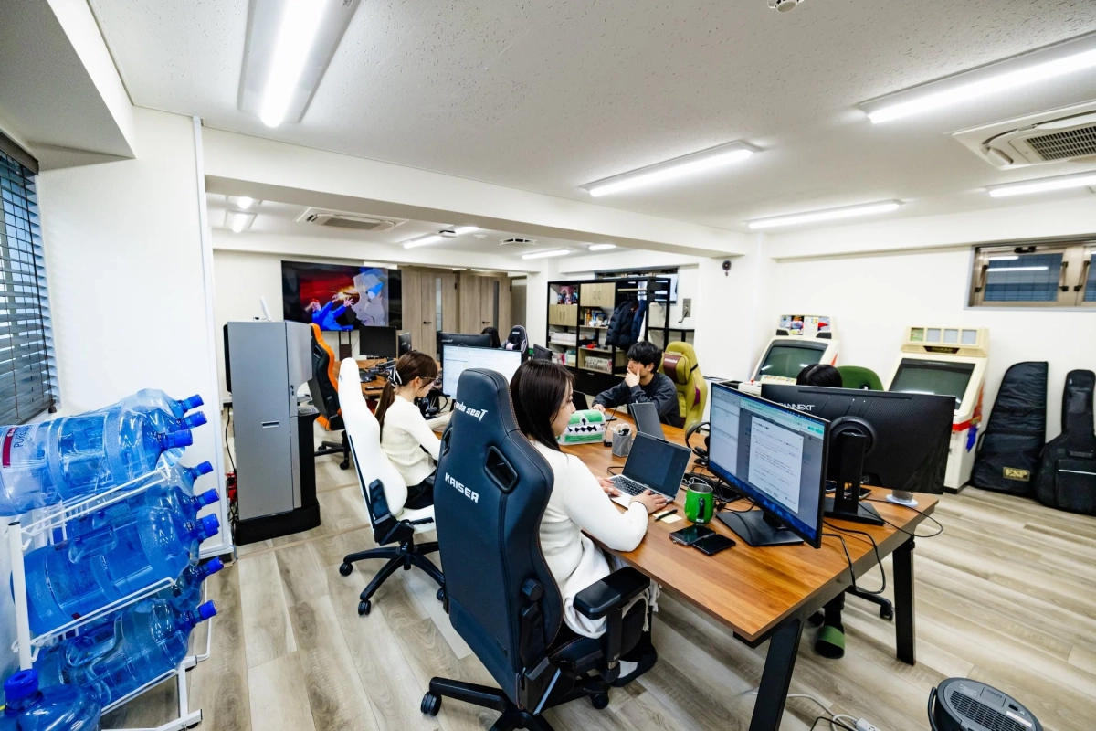 PC作業をする社員とアーケードゲーム機のあるオフィス風景