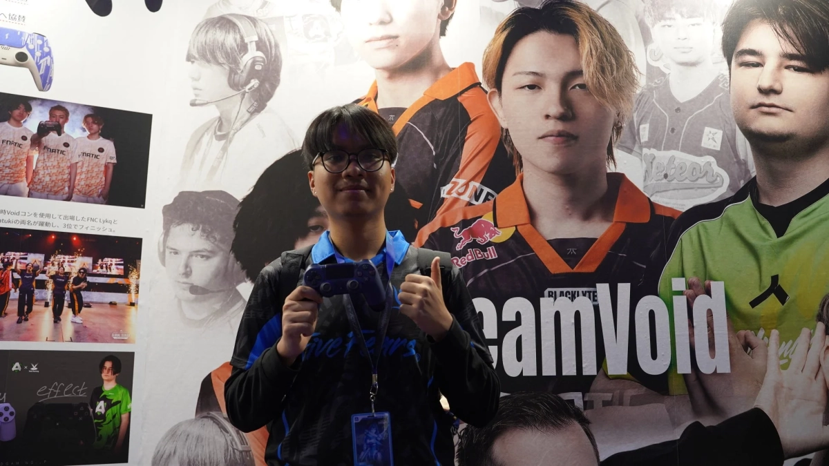 ゲームコントローラーを持ち親指を立てる若者