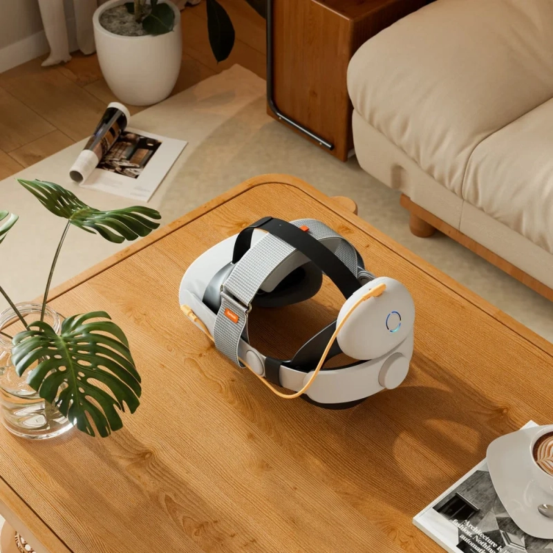 木目調のテーブルに白いVRヘッドセットが置かれ、その周りには観葉植物、雑誌、コーヒーカップが配置された、モダンなリビングルームの様子を捉えた画像です。