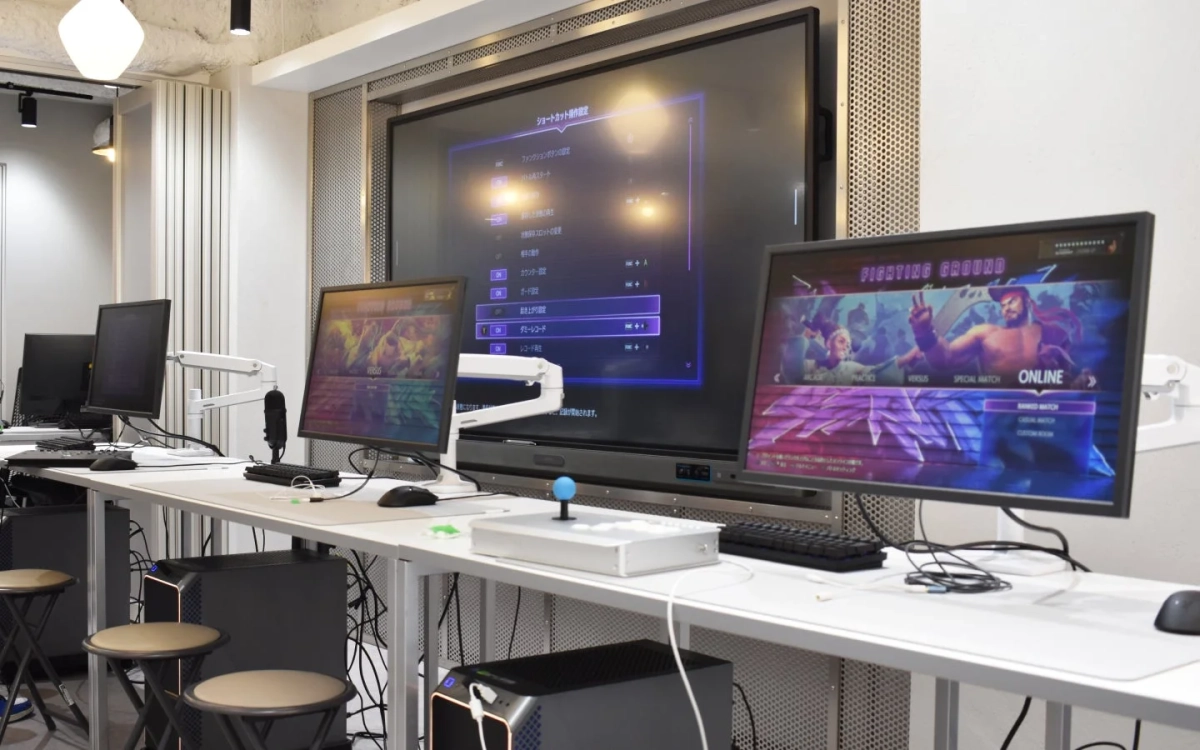 eスポーツ施設またはゲーミングカフェのような空間で、複数のモニターとゲーミングPCが並ぶモダンなゲーム環境