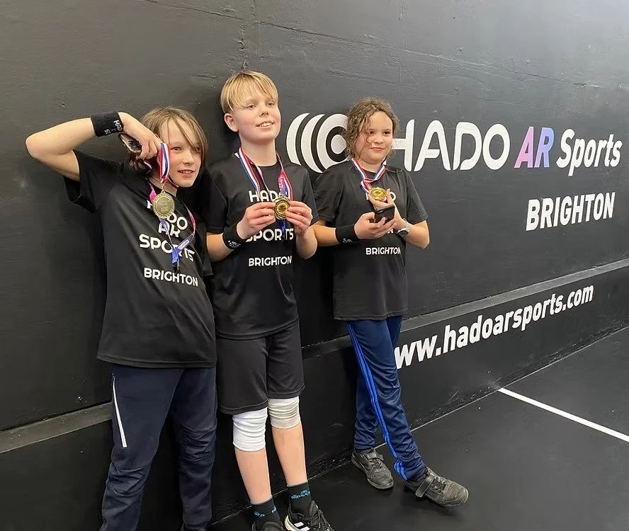 HADO ARスポーツのイベントでメダルを獲得し、誇らしげにポーズをとる3人の子供たち