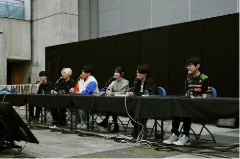 室内イベントで、複数の登壇者がマイクを前にパネルディスカッションを行っている様子