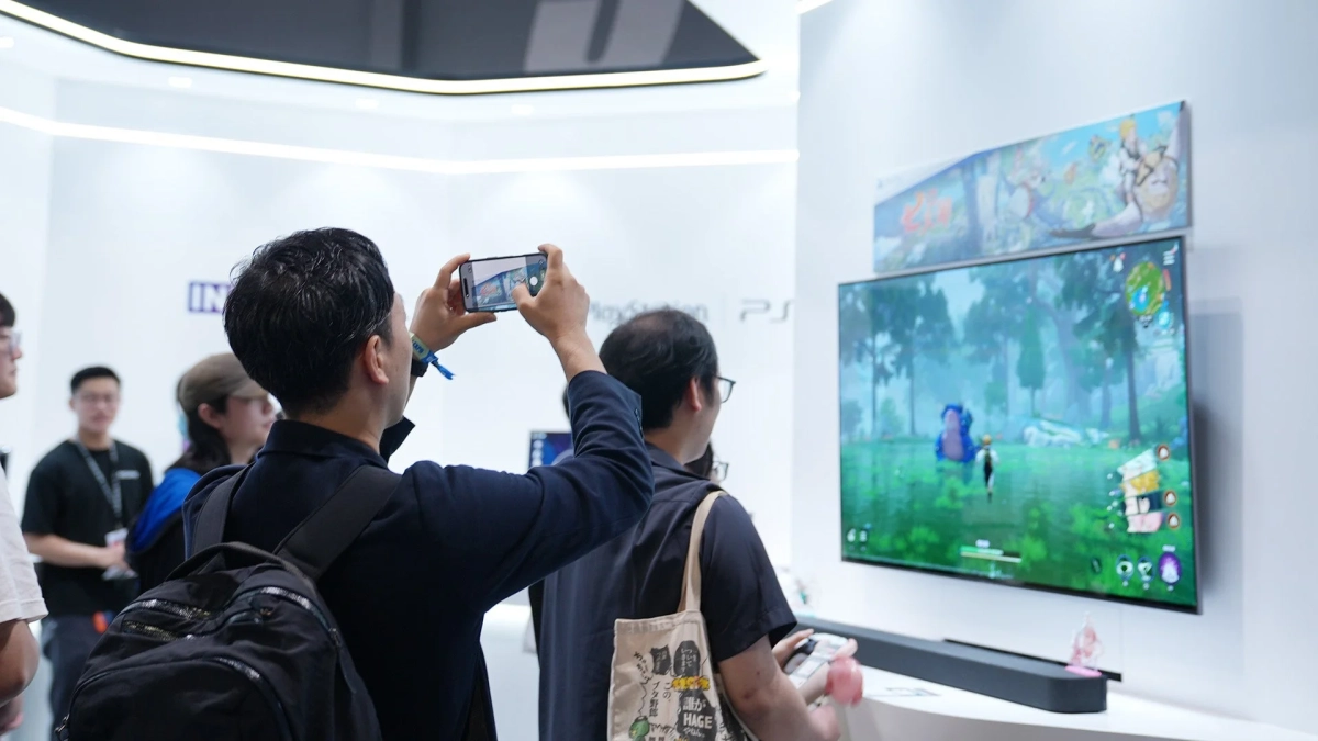 イベント会場でゲーム画面を撮影する来場者