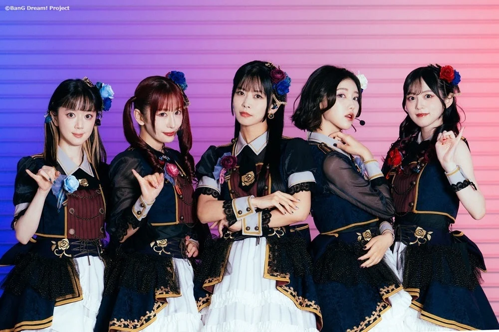 華やかな衣装の女性アイドルグループが笑顔でポーズをとっている