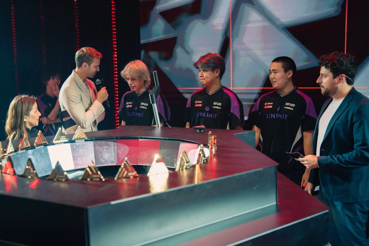 eスポーツイベントのステージで、司会者が「UNLIMIT」のユニフォームを着た選手たちにインタビューしている様子