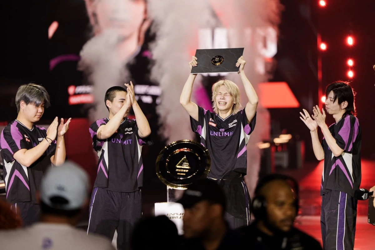 eスポーツ大会の表彰式で、UNLIMITチームの選手たちがMVPトロフィーを掲げ、優勝を祝っている様子