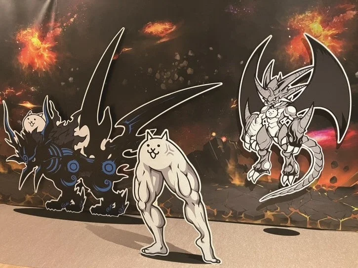 宇宙や炎のような背景の前でポーズをとるにゃんこ大戦争のキャラクターたち