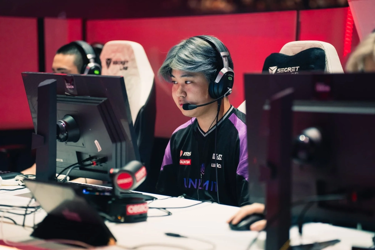 eスポーツの大会会場で、ヘッドセットを装着したゲーマーが真剣な表情でPCモニターに向かっている様子