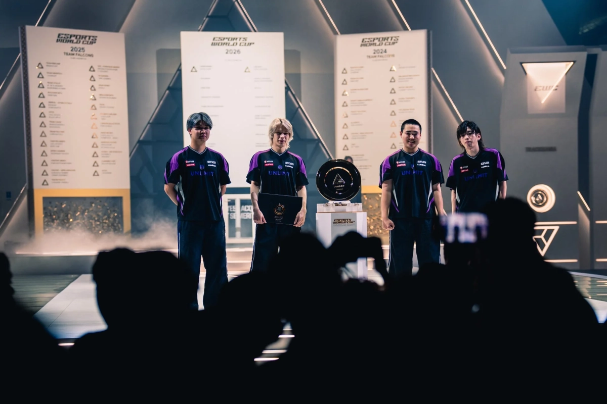 eスポーツイベントの表彰式で、ユニフォームを着た4人のチームメンバーがステージに立っている様子