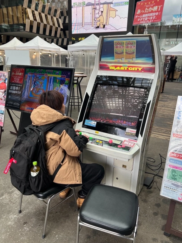 屋外でアーケードゲームをプレイする様子