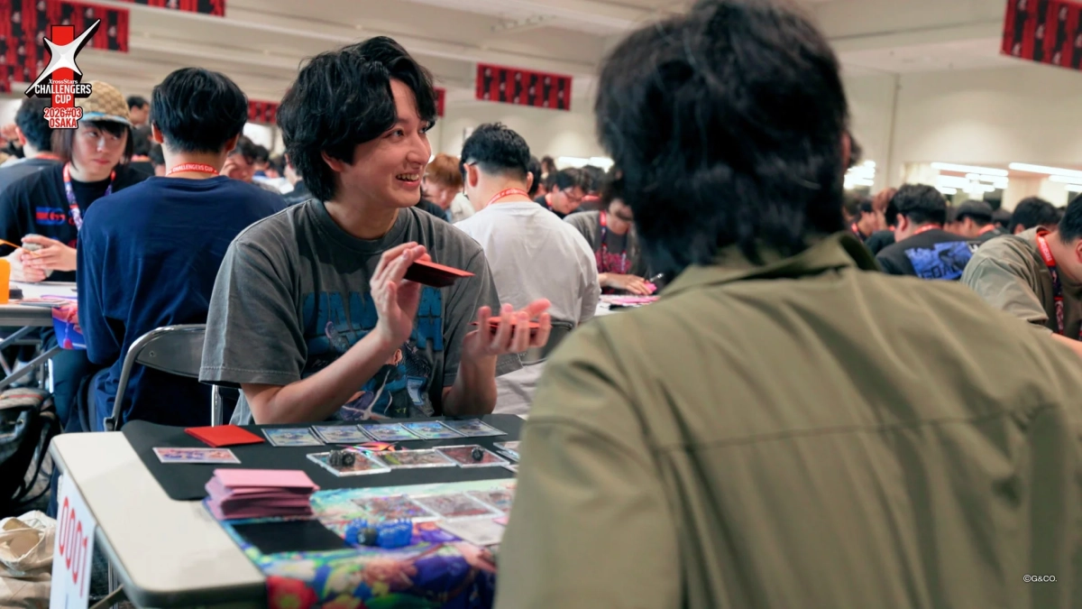 多くの参加者が集まる屋内イベントで、カードゲームに興じる人々