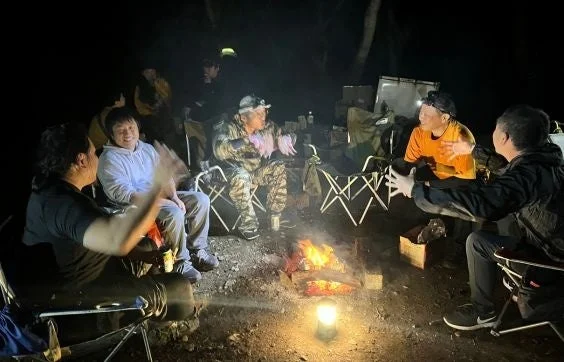 焚き火を囲んで談笑する男性たち