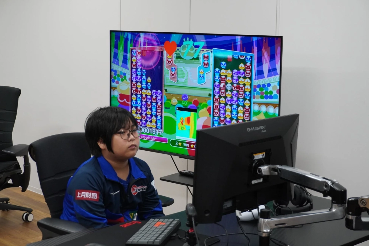 メガネをかけた若者がeスポーツのパズルゲームに集中している様子