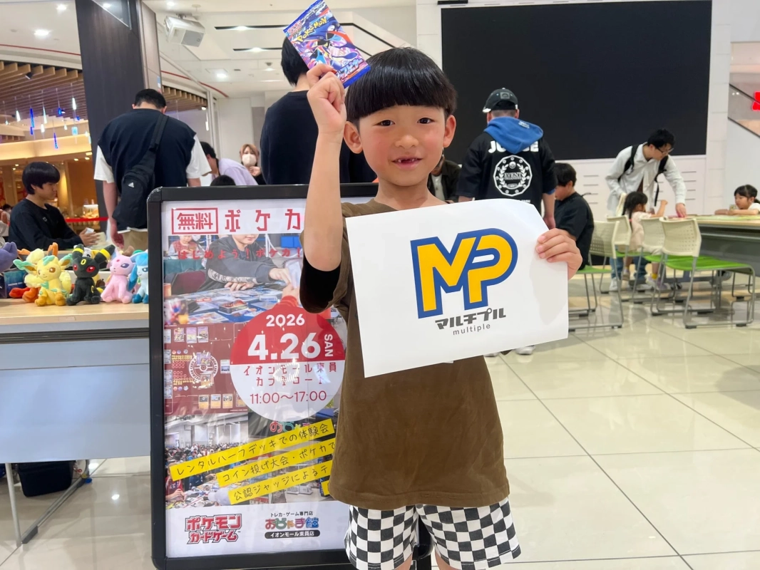 男の子がポケモンカードのパックとロゴ入り紙を持つ、イベントの様子