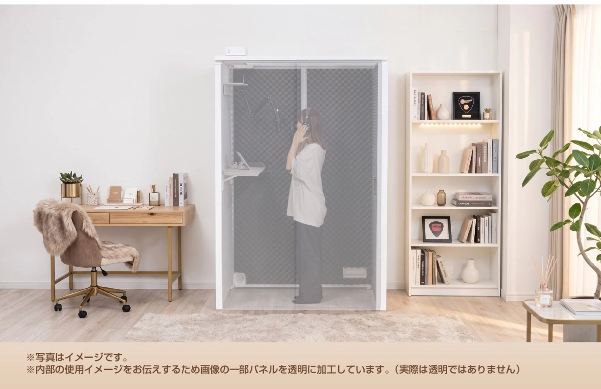 モダンなインテリアの部屋に設置された防音室で、女性がマイクとヘッドホンを使用している様子